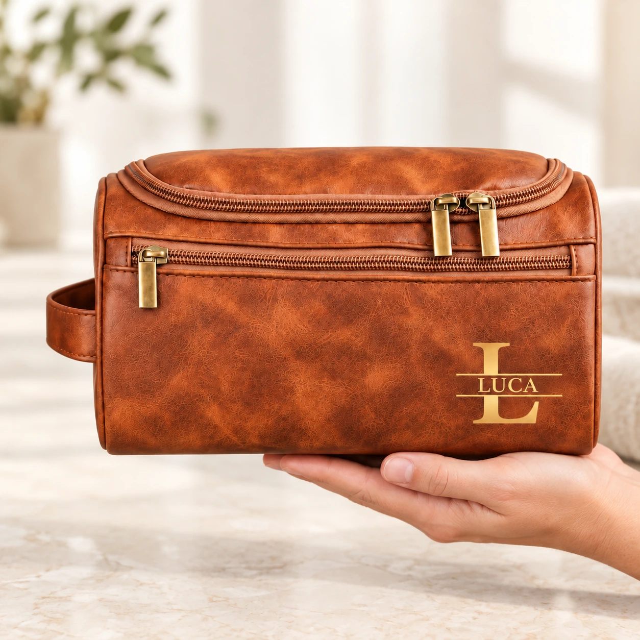 Cognac LUCA monogram toiletry bag supported by one right hand